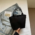 Minimalistische schwarze Stofftasche mit Fashion-Label in lässigem Lifestyle-Ambiente - Schwarz