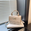 Petit sac vintage blanc cassé avec nœud doré et poignée nouée posé sur un livre - Kaki