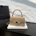 Bolso de mano minimalista en cuero caqui con asa redonda y hebilla plateada sobre piedra - Caqui