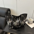 Black textured tote bag with colorful striped embroidery and leather handles on desk - Black