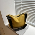Ginger yellow crescent nylon shoulder bag with adjustable black strap on a book - Yellow