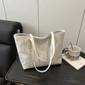 White tote bag with colorful wavy embroidery and gold stud details on dark wood table - White