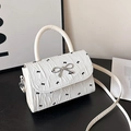 White shoulder bag featuring black bow patterns and a silver metallic bow buckle - White