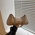 Detail of beige baguette bag with gold buckle and knot strap on a white window sill - Khaki