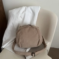 Bolso bandolera minimalista de pana beige en forma de concha sobre una silla elegante - Caqui
