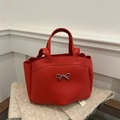 Red leather tote bag with silver bow accent and spacious interior for 2025 summer - Red