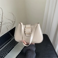 Minimalistische beige Umhängetasche mit goldener Schnalle auf einem schwarzen Schreibtisch - Khaki