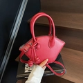 Red minimalist bucket bag with woven charm accessory on a wooden background - Red