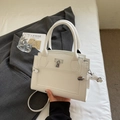 White lychee grain leather handbag with silver lock, shown with grey blazer on white bedding - Off-white