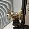 Borsa sottobraccio con paillettes dorate e tracolla in pelle sotto una luce artistica - Oro