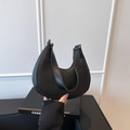 Bolso de hombro minimalista de media luna en cuero negro con patrón de lichi por modelo - Negro
