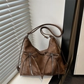 Brown bow shoulder bag with vertical zippers and adjustable strap on window sill - Brown