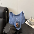 Bolso de hombro denim azul con lazos rosas sobre fondo de mesa de madera oscura - Azul oscuro