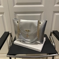 Silver metallic leather tote bag with gold chain strap and deer charm on chair - Silver