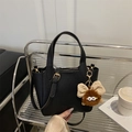Bolso cubo de cuero negro con asas y colgante de peluche sobre una silla de metal - Con Colgante / Negro