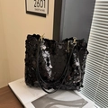 Modische schwarze Pailletten-Tasche mit goldener Kette auf einem Holztisch-Arrangement - Schwarz