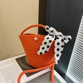 Secchiello intrecciato arancione con bottone di perla e foulard a pois su rivista - Arancione