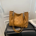Bolso tote caramelo con estampados de dibujos y correa de cadena sobre taburete - Marrón