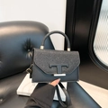 Borsa a tracolla nera con patta glitterata e dettaglio a T su sedia in pelle nera - Nero