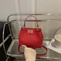 Sac seau rouge chic texture litchi avec fermoir doré sur support d'exposition élégant - Rouge