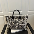 Große Shopper-Tasche mit Leopardenmuster, weißen Fransen und schwarzen Stoffgriffen am Stuhl - Schlichter Stil