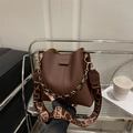 Dark brown textured leather bucket bag with gold chain and patterned strap - Brown