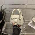 Mini cream square crossbody bag with silver buckle and chain strap shown in a lifestyle view - White