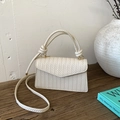 Chic cream woven texture crossbody flap bag with elegant knotted handle on wooden desk - White