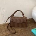 Detail of deep brown woven texture and knot handle on a stylish crossbody bag - Brown