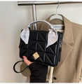 Close-up of black quilted handbag with golden twist lock and decorative paisley silk scarf - Black