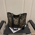 Großer Shopper mit Leopardenmuster und schwarzen Lederriemen auf modernem Stuhl - Schwarz