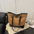 Brown quilted suede tote bag with black trim and long shoulder straps on a cozy blanket - Brown