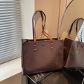 Large dark brown tote bag with matte leather finish and golden rivet details on the straps - Coffee