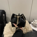 Bolso cubo trenzado negro con cadena dorada en un ambiente de estilo de vida acogedor - Negro