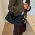Bolso tote negro minimalista de media luna llevado al hombro por una modelo - Negro