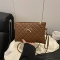 Brown quilted crossbody bag with gold bow buckle held by hand in a stylish setting - Brown