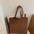 Detailopname van een donkerbruine suède tote bag rustend op een houten stoel - Koffie zonder Hanger