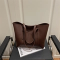 Bolso tote grande de cuero marrón oscuro con costuras minimalistas en una silla negra - Marrón