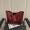 Bolso tote grande minimalista en cuero rojo vino sobre una revista blanca y asiento negro - Rojo