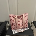 Pink tote bag with red cherry print and golden fashion text detail on a black chair - Pink