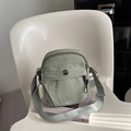 Bolso bandolera de nailon verde claro con logotipo M FASHION sobre una silla blanca moderna - Verde