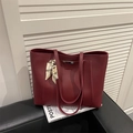 Large burgundy tote bag with metallic detail and silk scarf on a black leather surface - Red