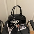 Glossy black patent leather Boston bag with a pearl bow charm and adjustable strap - Black