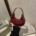 Chic burgundy patent leather crescent handbag with glossy finish and gold metal accents - Red