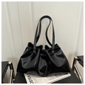 Glossy black pleated bucket bag with long shoulder straps on a sleek chair - Black