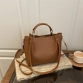 Brown lychee leather tote bag with dual handles and adjustable strap in a cozy setting - Brown