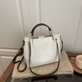 White pebbled leather tote with brown straps and gold hardware on a cozy background - White