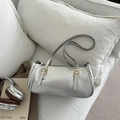 Silver metallic underarm shoulder bag with golden buckles on a white texture sofa - Silver