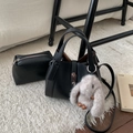 Detail view of black litchi pattern bucket bag with silver buckle and rabbit charm - With Charm / Black