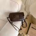 Detail of dark brown glossy crossbody bag featuring spiral knots and rectangle buckle - No Pendant / Brown